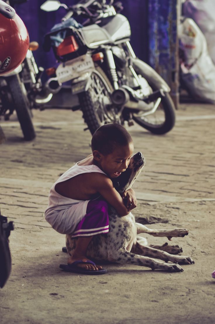 a young boy kneeling down next to a dog