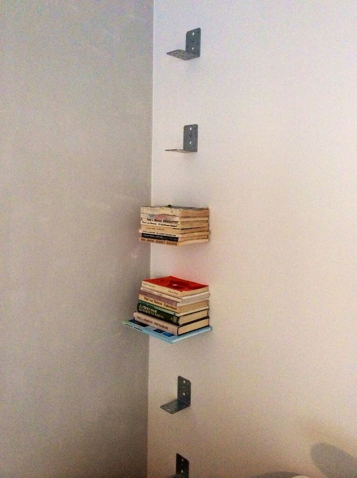 three books are stacked on top of each other in the corner of a room with white walls