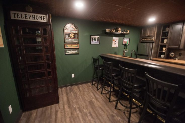 there is a bar in the middle of this room with stools at the counter