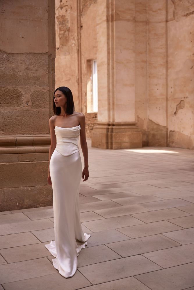 a woman in a long white dress standing on the ground with her back to the camera