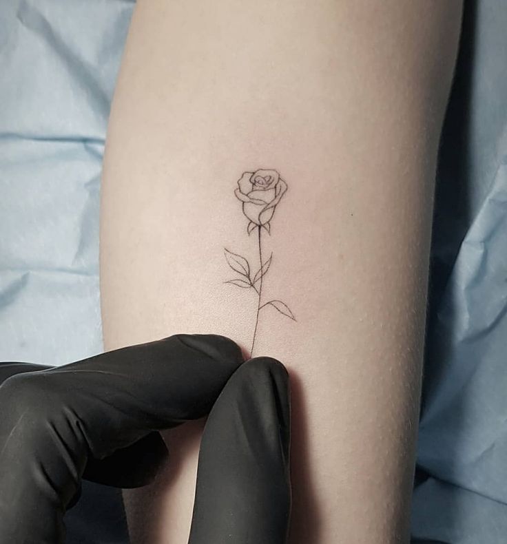 a woman's arm with a small rose tattoo on the left side of her thigh