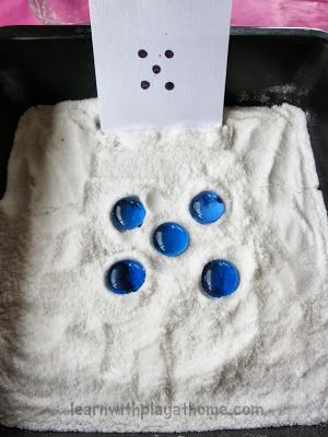 a black pan filled with white powder and blue buttons