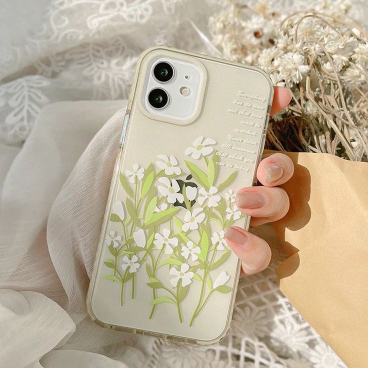 a woman's hand holding an iphone case with flowers on it