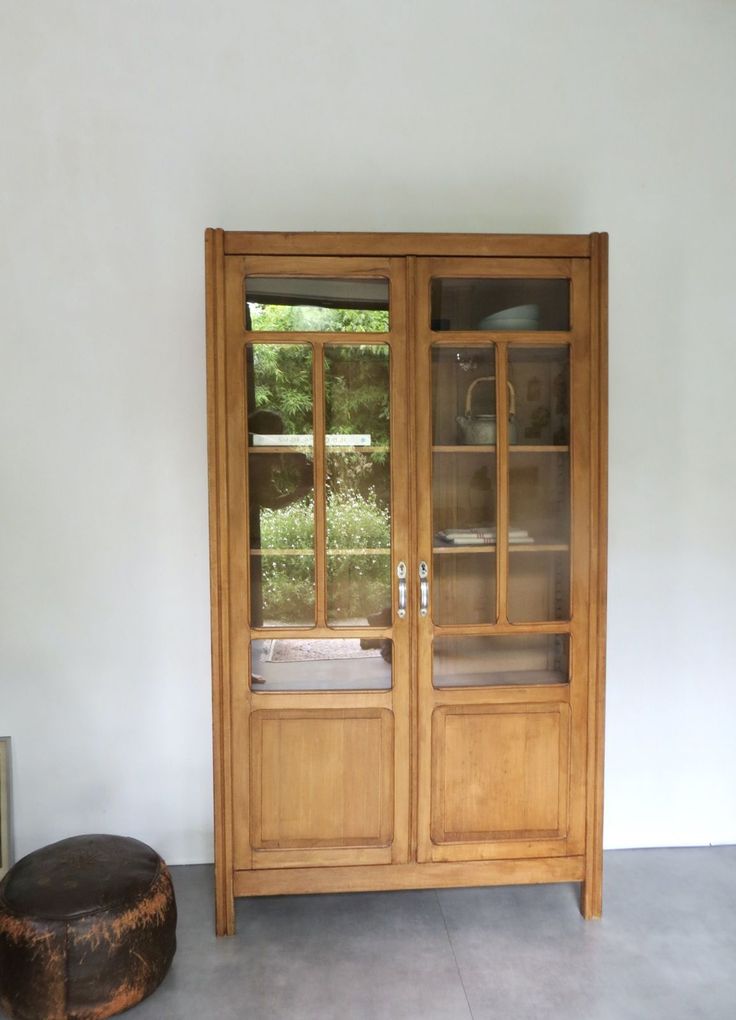 a wooden cabinet sitting next to a window in a living room with concrete flooring