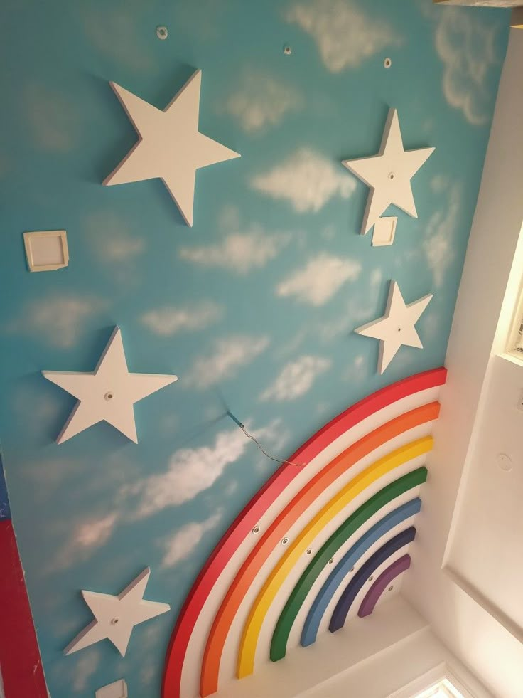 there is a rainbow and stars painted on the wall in this children's room