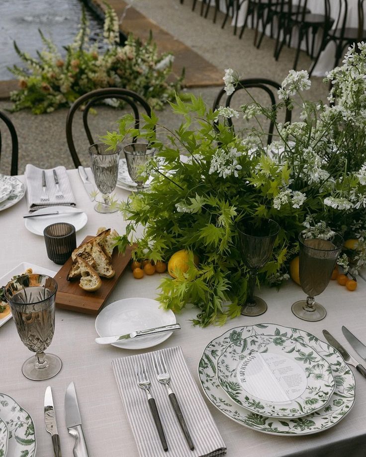 the table is set with plates, silverware and flowers in vases on it