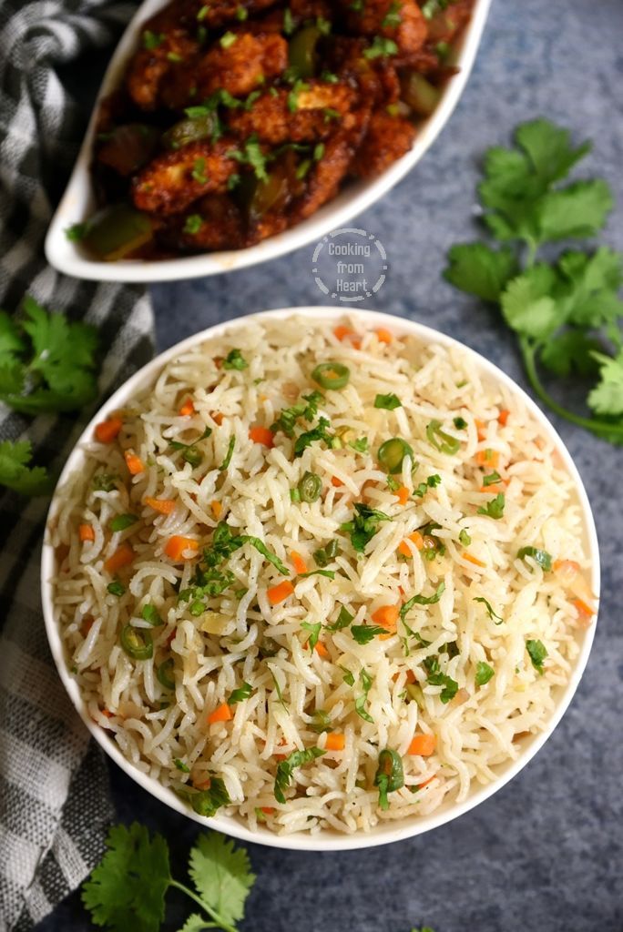 two bowls filled with rice and vegetables on top of a blue table cloth next to cilantro