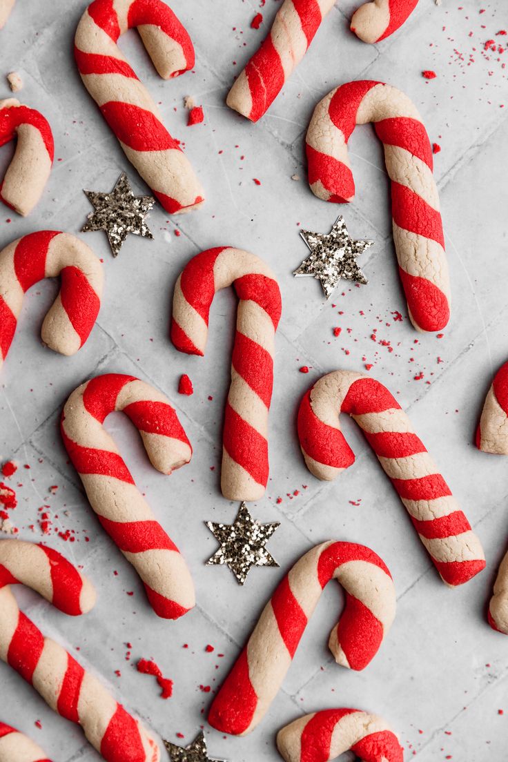 red and white candy canes on a baking sheet with glitter sprinkles