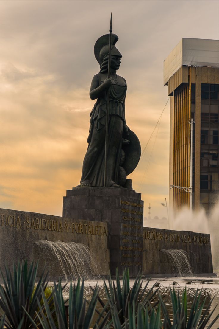 there is a statue in front of a fountain with water spouting from it