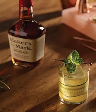 a bottle of miller's mark next to a glass with a cucumber garnish