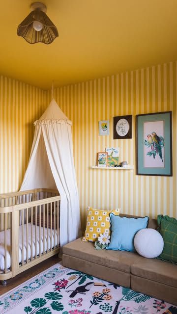 a baby's room with yellow striped walls and a white canopy over the crib