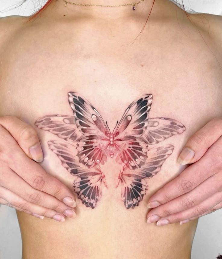 a woman's chest with a butterfly tattoo on it and two hands holding the back of her stomach