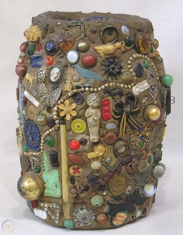 a close up of a vase made out of buttons and other items on a white surface