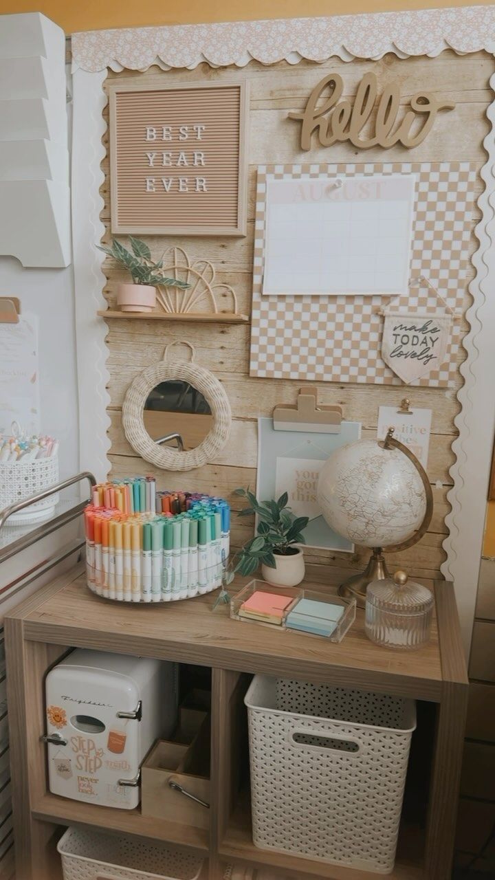 a desk with many items on it and some pictures hanging above the top, along with other office supplies