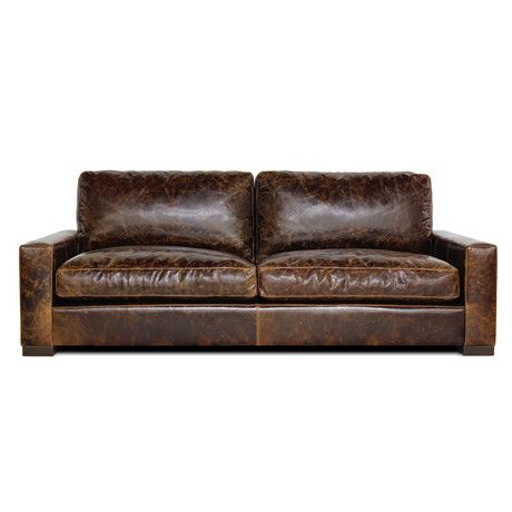 a brown leather couch sitting on top of a white floor