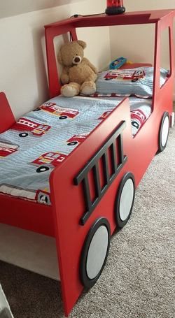 there is a bed with a train theme and a teddy bear sitting on the top