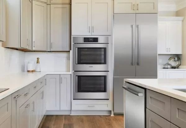 a kitchen with white cabinets and stainless steel appliances in the center, along with wood flooring