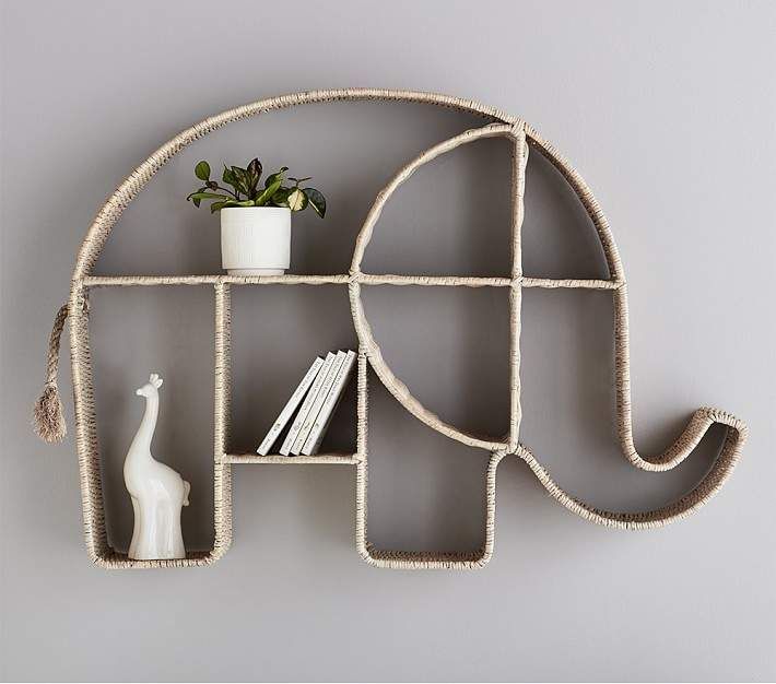 an elephant shaped shelf with books and vases on it's sides, against a gray wall