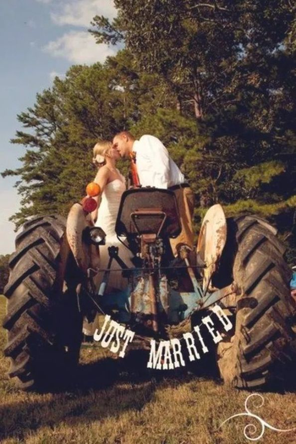 a man and woman kissing on top of a monster truck in the middle of a field