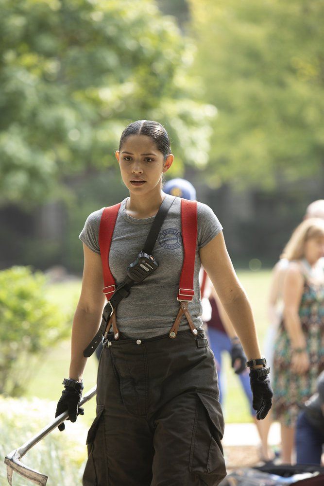 a woman walking down the street with an ax in her hand and other people behind her