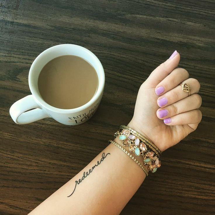 a woman's arm with two bracelets on it and a cup of coffee