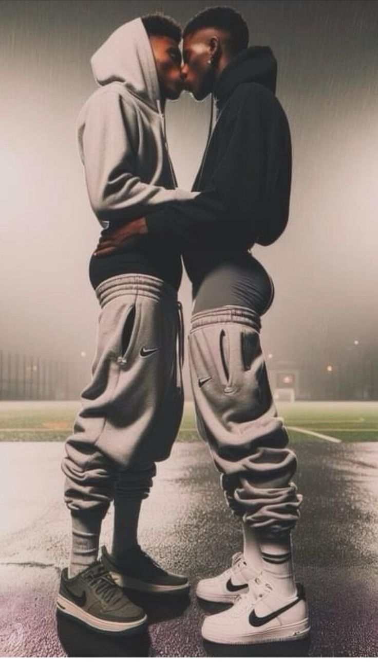 two young men standing next to each other in front of an empty parking lot at night