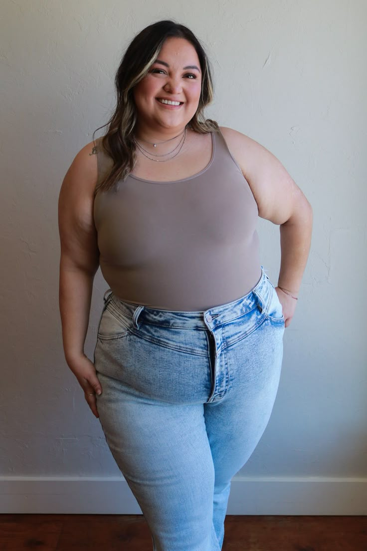 a woman standing in front of a wall with her hands on her hips and smiling