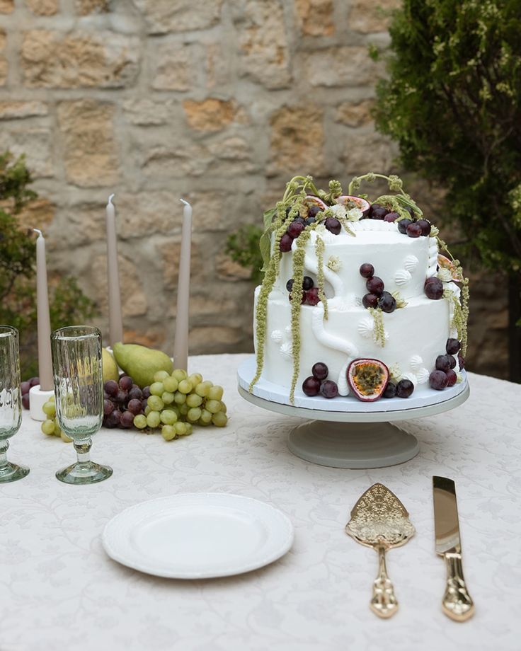 a white cake sitting on top of a table next to wine glasses and silverware