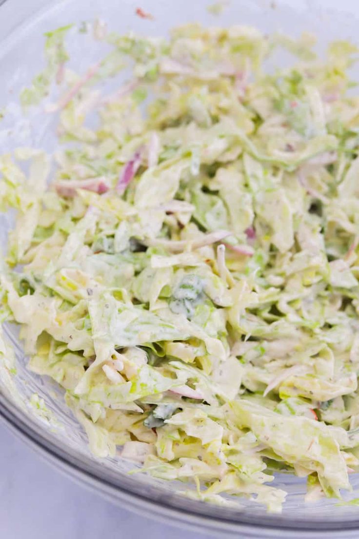 a glass bowl filled with coleslaw on top of a table