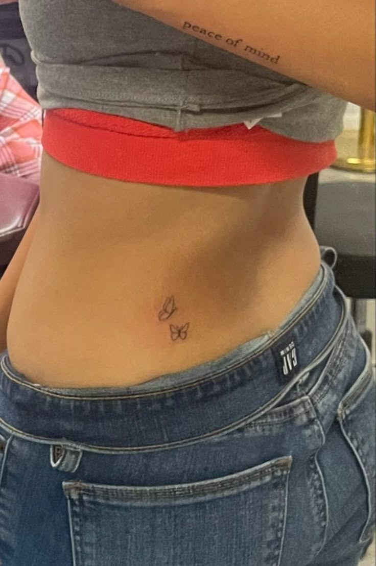 a woman's stomach with a small butterfly tattoo on her lower back and side