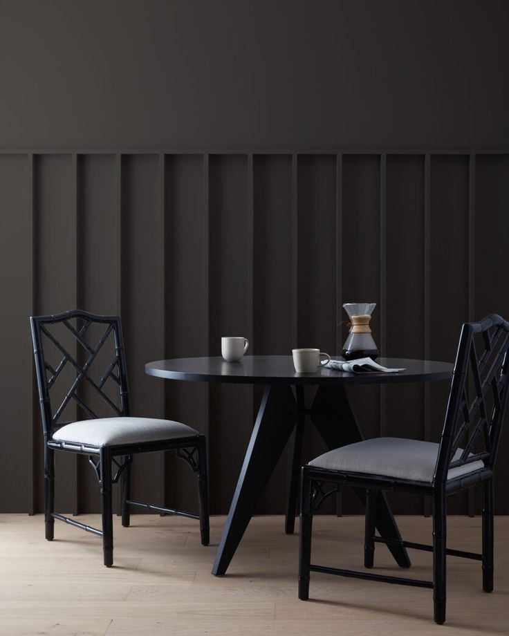 two chairs and a table in front of a wall with vertical slats on it