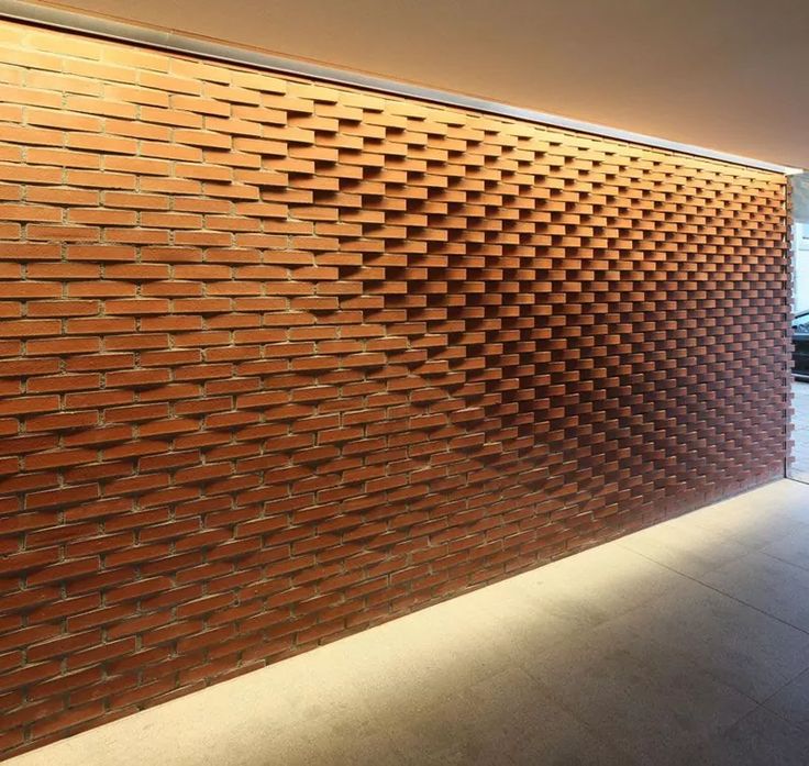 a large brick wall in the middle of a room with concrete flooring and walls made out of bricks