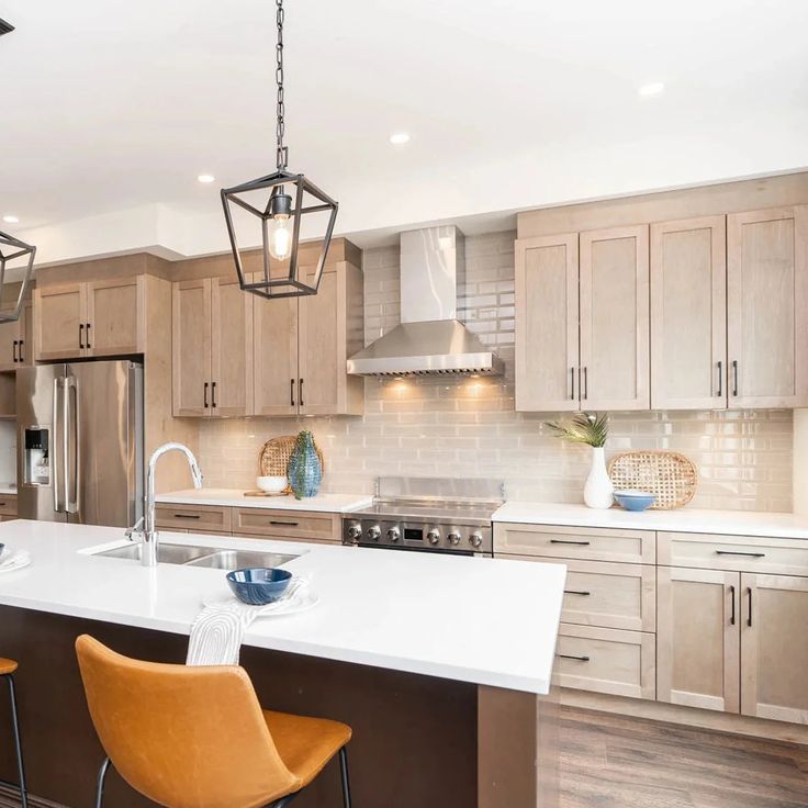 a large kitchen with an island and two pendant lights hanging from it's ceiling