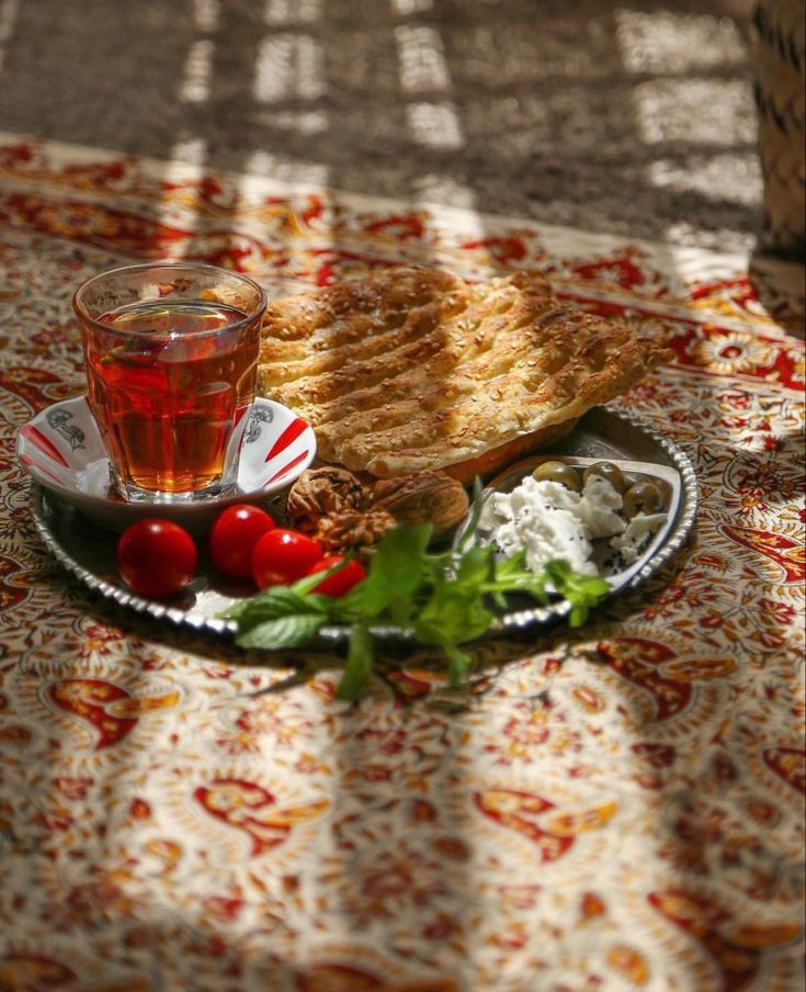 a plate full of food and a cup of tea on a tablecloth with flowers