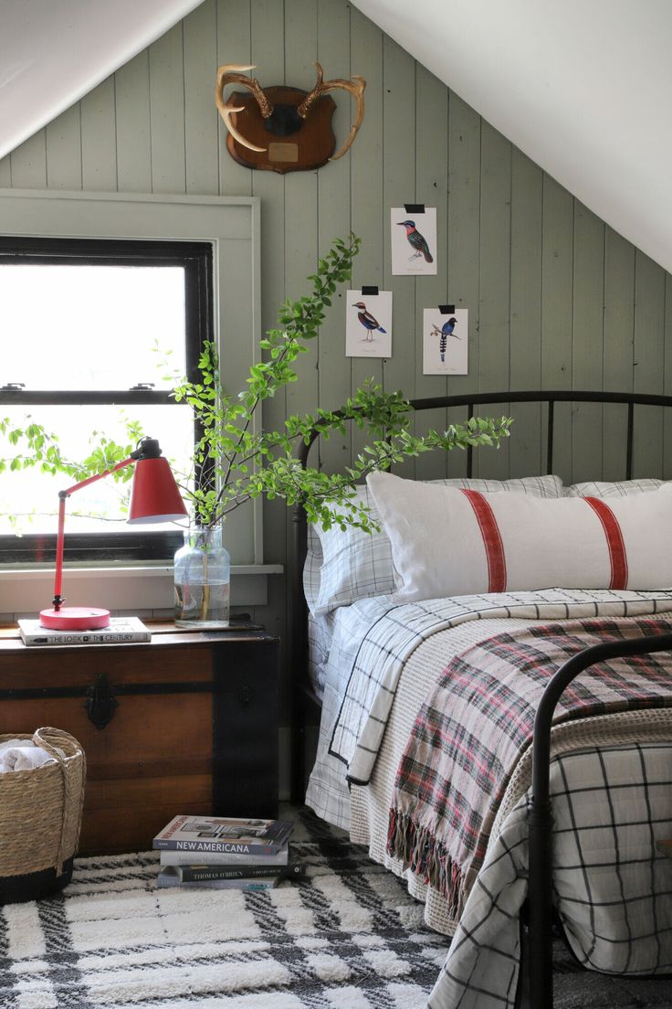 a bed room with a neatly made bed next to a window and a plant in a vase