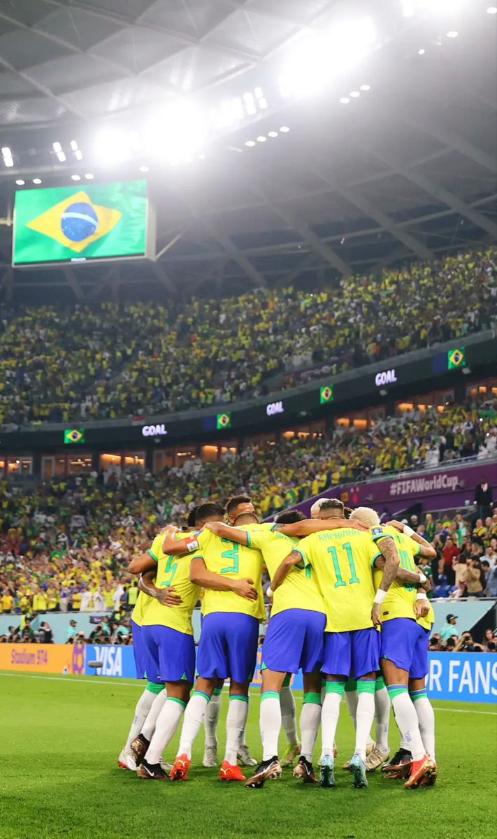 a group of soccer players huddle together on the field in front of an audience