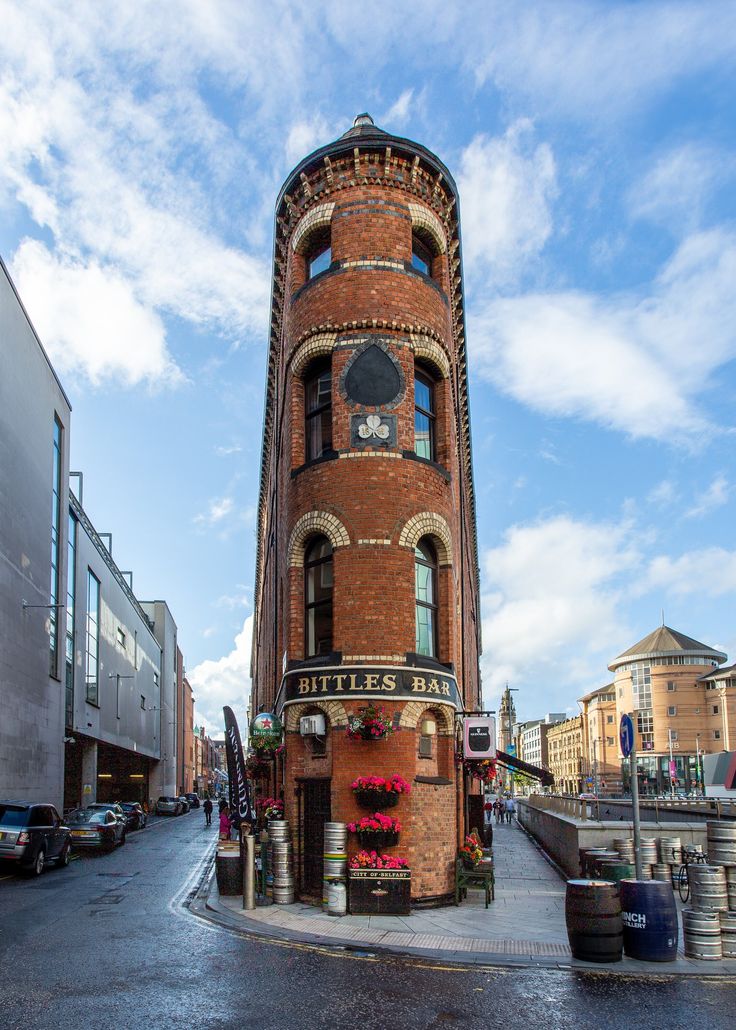 a tall brick building sitting on the side of a road next to parked cars and buildings