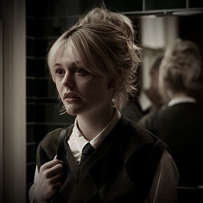 a woman standing in front of a mirror wearing a vest and tie