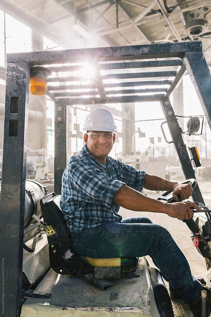 a man sitting on the back of a forklift in a warehouse by jordi for stocks