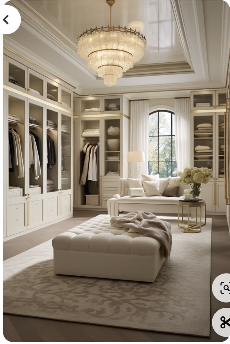 an elegant walk in closet with white furniture and chandelier