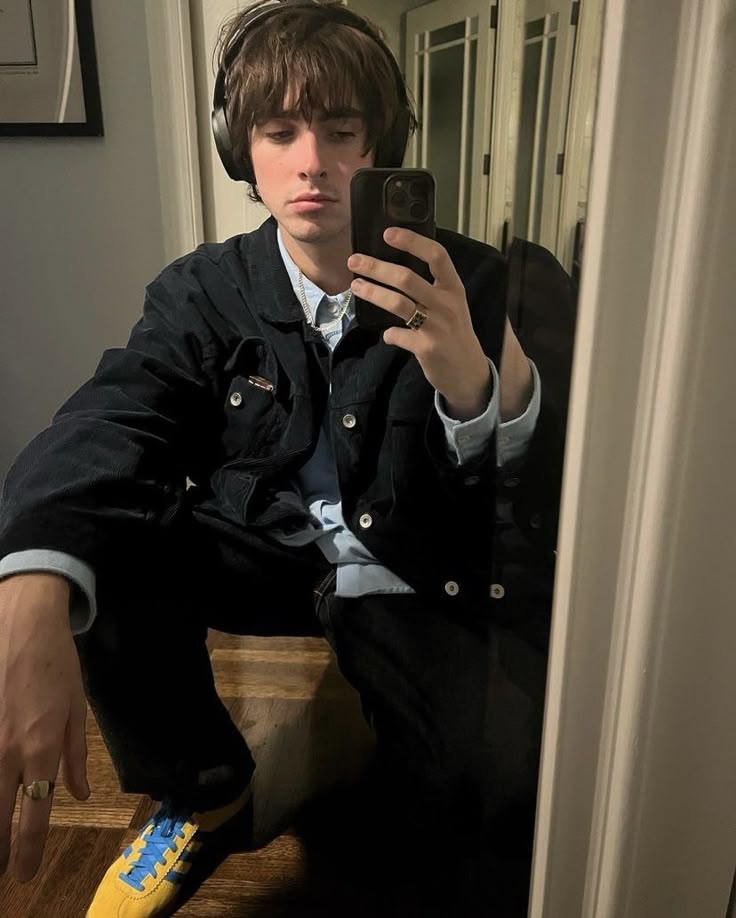 a young man wearing headphones is taking a selfie in the mirror with his cell phone