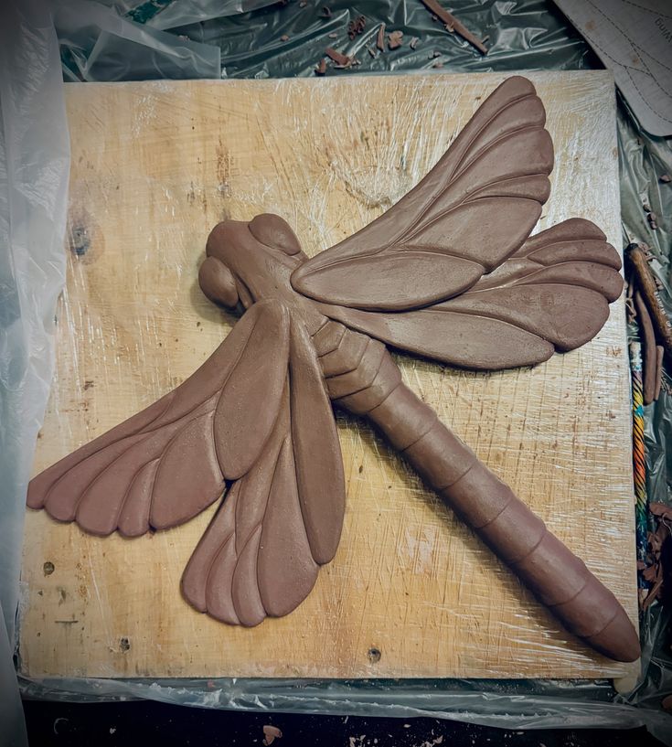 a carving of a dragonfly on a piece of wood