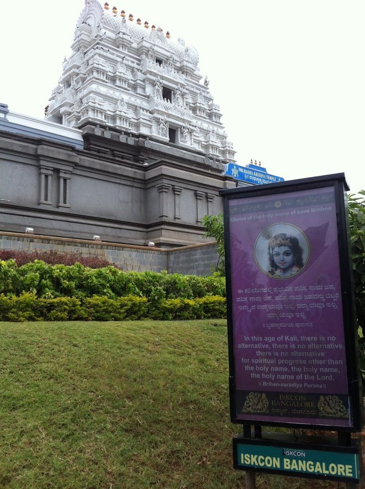 a sign in front of a large building with a statue on it's side