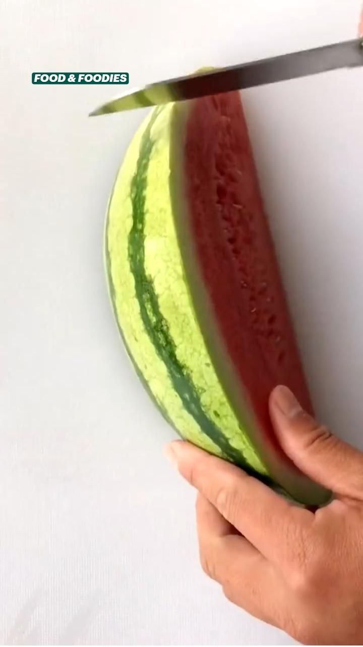 a person cutting a watermelon with a knife