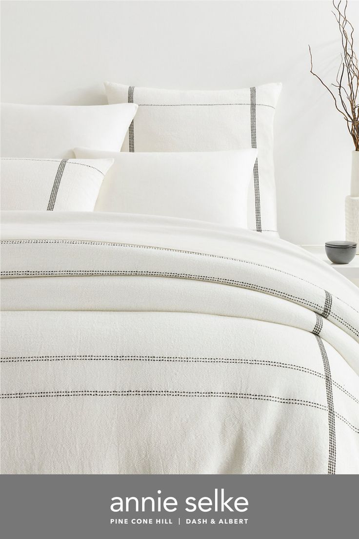 an image of a bed with white linens and grey lines on the comforter