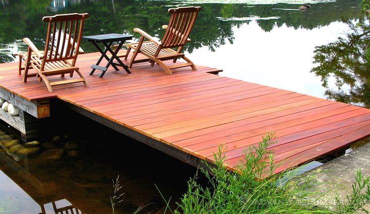 two wooden chairs sitting on top of a dock