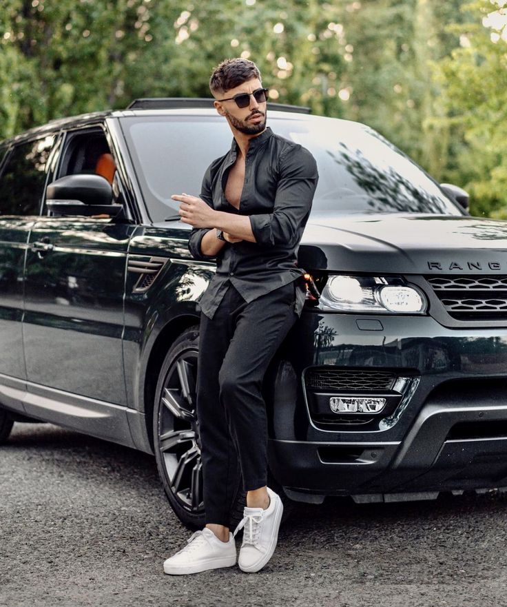 a man sitting on the hood of a black range rover