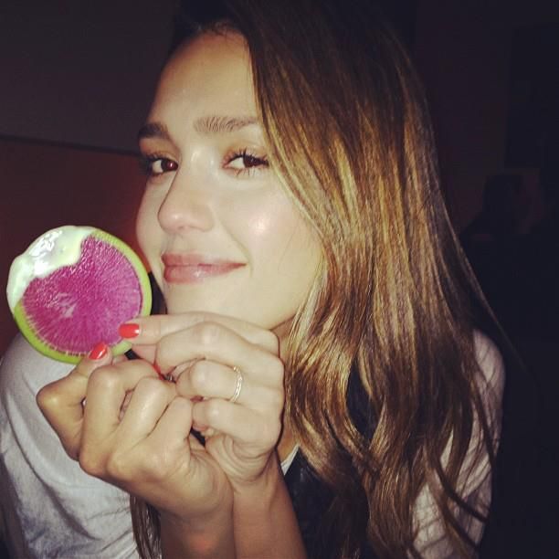 a woman holding a piece of fruit up to her face