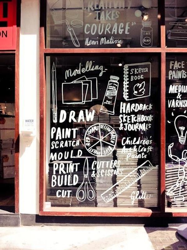 a store front with chalk writing on the glass and door, along with other signs