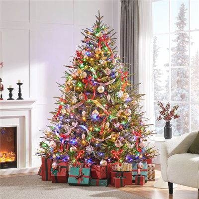 a brightly lit christmas tree in a living room with presents on the floor and fireplace